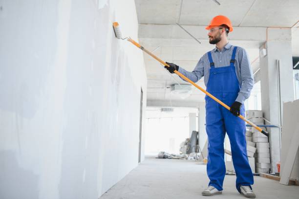 painter man painting the wall, with paint roller.